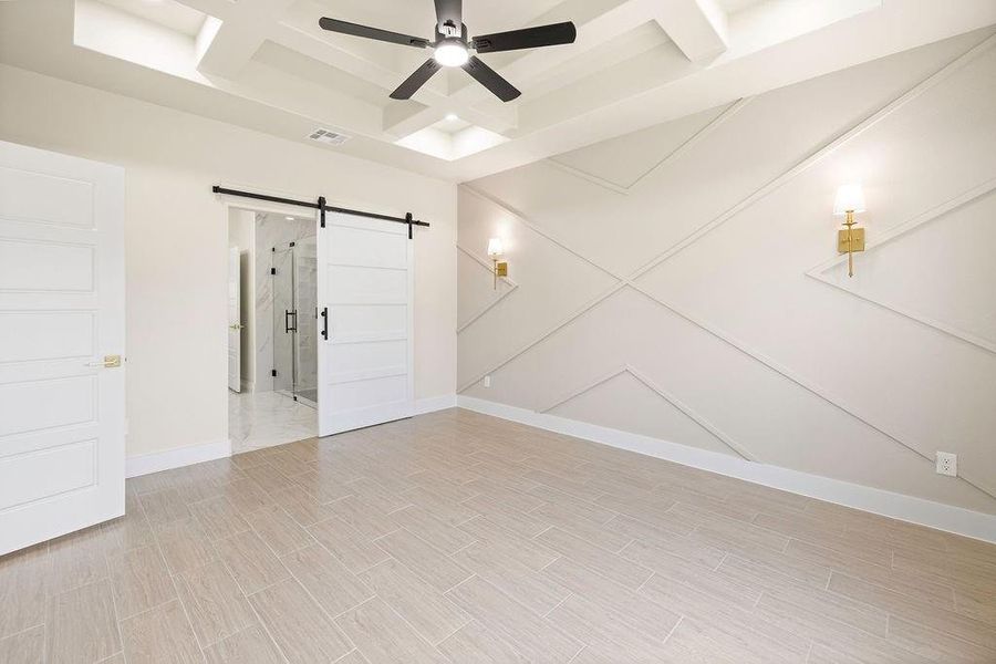 Unfurnished room with wood finish floors, visible vents, a barn door, ceiling fan, and baseboards