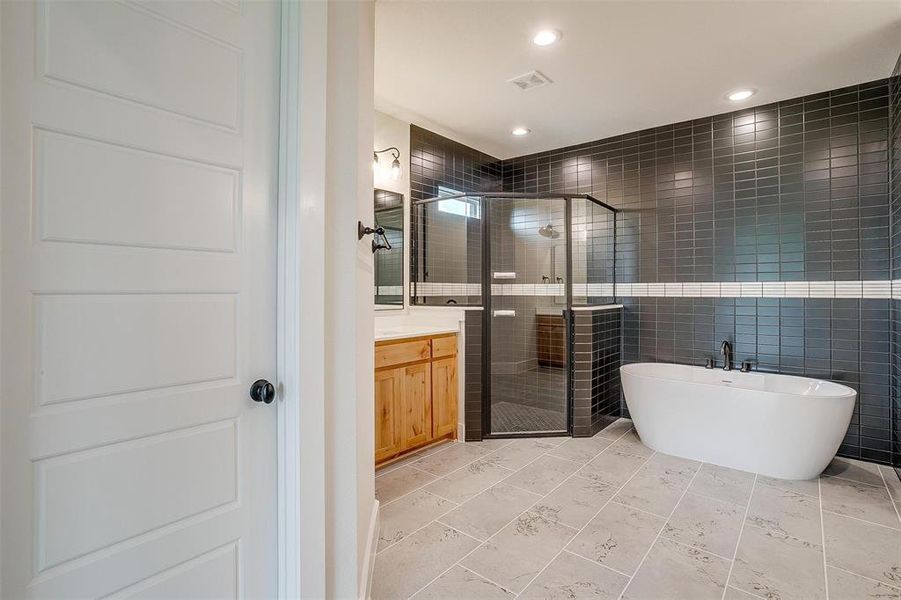 Bathroom featuring tile flooring, separate shower and tub, vanity, and tile walls