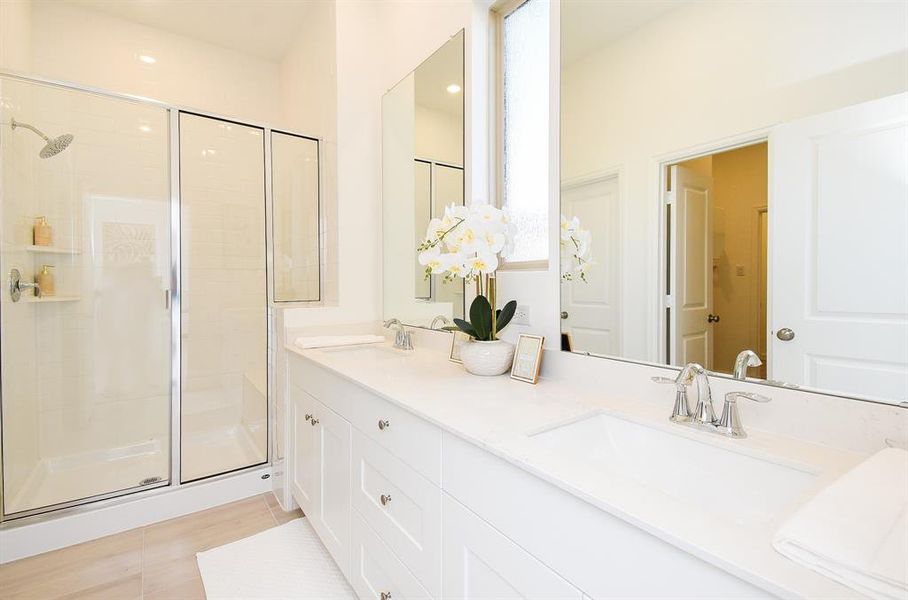 Luxurious white walls and built-in cabinetry fill your primary ensuite bath, shown here with roomy walk-in shower and dual sinks, under simple streamlined wall mirrors.