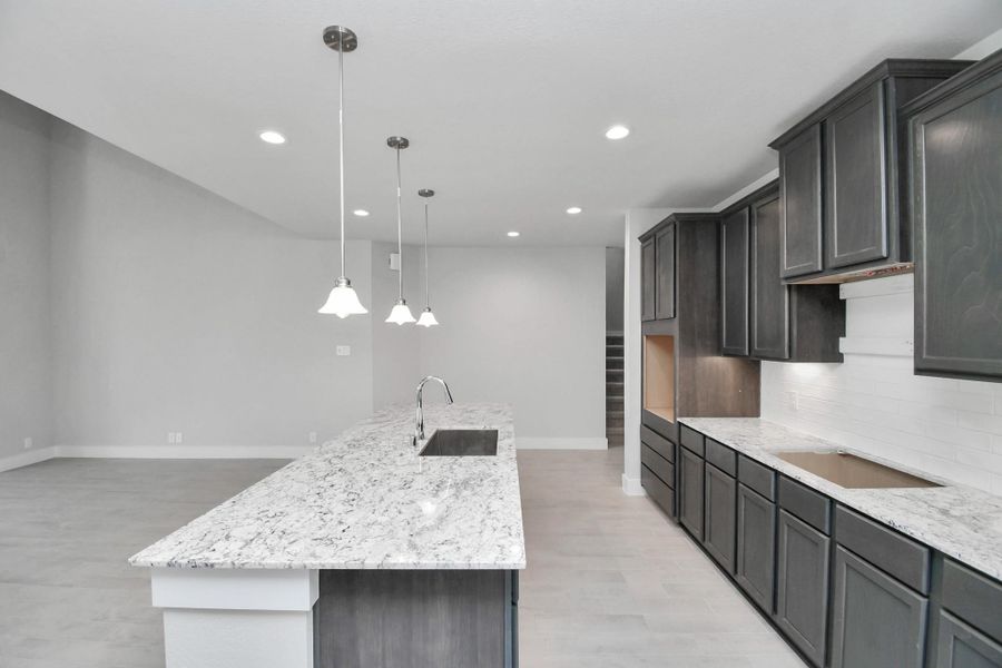 The kitchen is a culinary haven, featuring granite countertops, a tile backsplash, stainless steel appliances, 42” upper cabinets, and undercabinet lighting. Sample photo of completed home with similar floor plan. Actual colors and selections may vary. The kitchen is a culinary haven, featuring granite countertops, a tile backsplash, stainless steel appliances, 42” upper cabinets, and undercabinet lighting. Sample photo of completed home with similar floor plan. Actual colors and selections may vary.