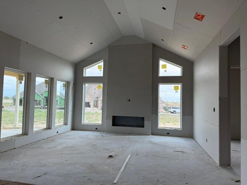 Unfurnished living room featuring high vaulted ceiling, plenty of natural light, and a large fireplace Unfurnished living room featuring high vaulted ceiling, plenty of natural light, and a large fireplace