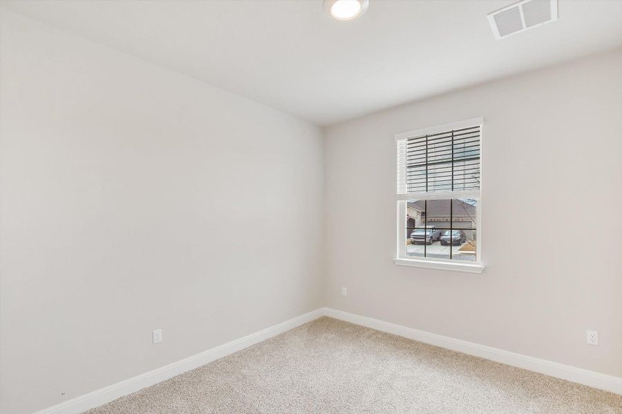 Carpeted spare room featuring visible vents and baseboards