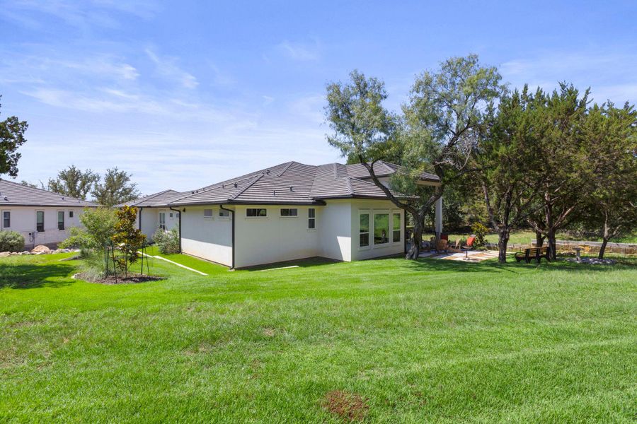 A verdant backyard with mature trees and a flagstone patio offers serene outdoor living.