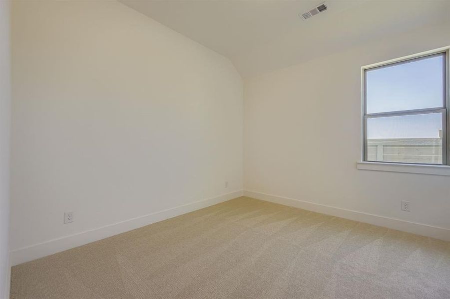 Empty room with light carpet and lofted ceiling Empty room with light carpet and lofted ceiling