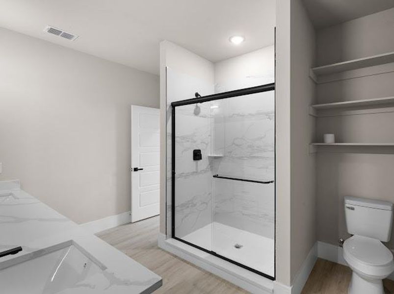 Full bathroom featuring light wood-style floors, double vanity, and a marble finish shower