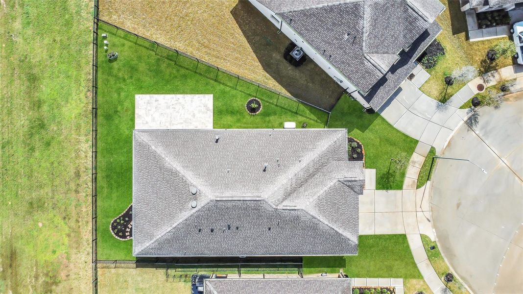 Overhead view of the home displaying the roofline, lot layout, and surrounding green space within the neighborhood.
