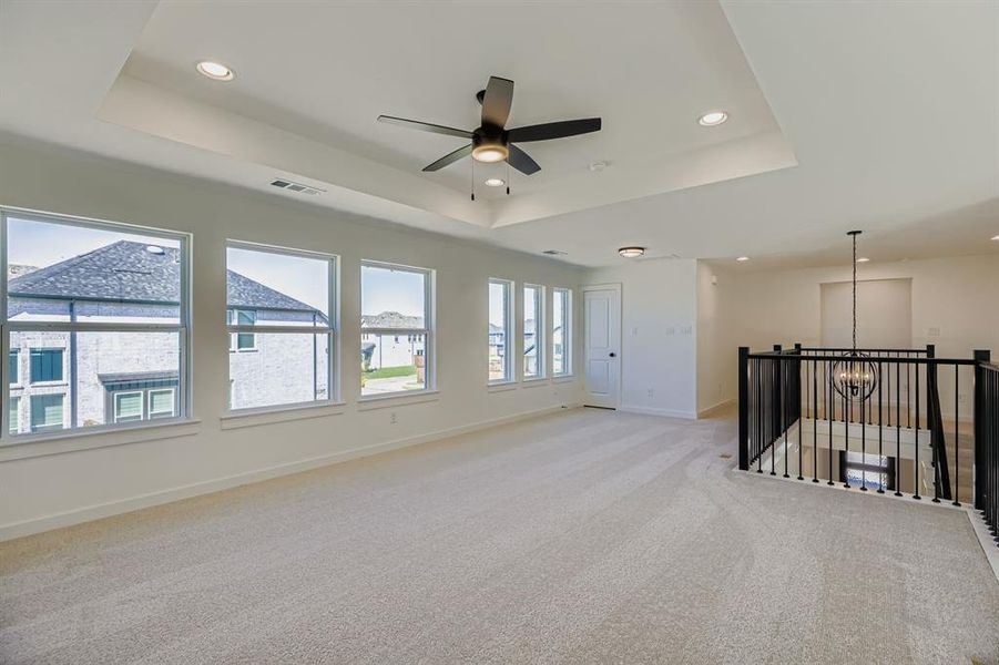 Empty room with a tray ceiling, light carpet, recessed lighting, a ceiling fan, and a chandelier Empty room with a tray ceiling, light carpet, recessed lighting, a ceiling fan, and a chandelier