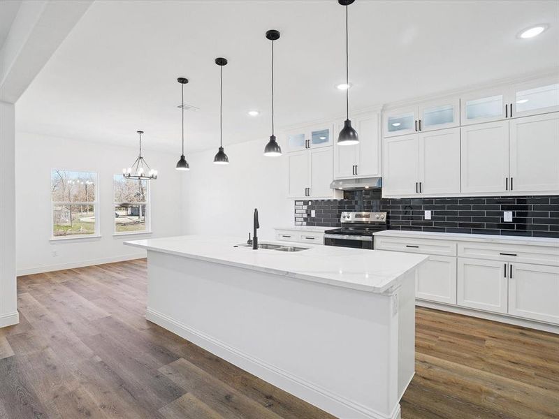 Kitchen featuring glass fronted cabinets, stainless steel electric range oven, backsplash, and white cabinetry