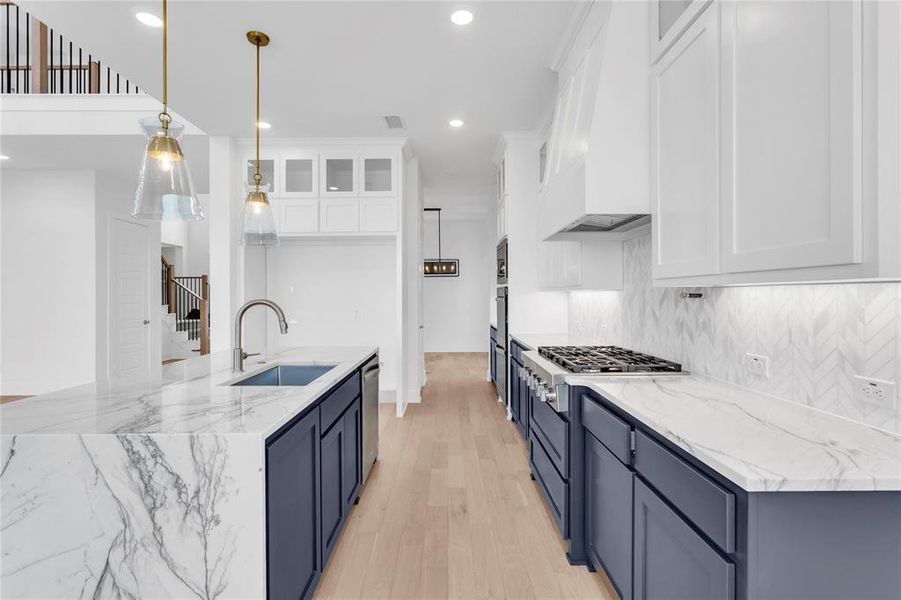 Kitchen featuring light stone countertops, light wood-type flooring, white cabinetry, glass insert cabinets, and recessed lighting