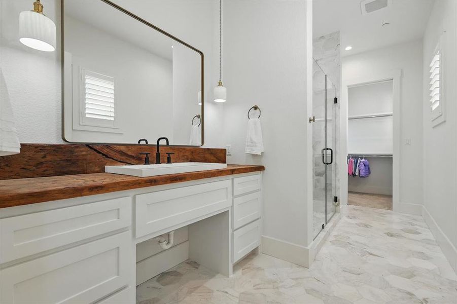 Full bathroom with a shower stall, marble finish floors, vanity, and healthy amount of natural light Full bathroom with a shower stall, marble finish floors, vanity, and healthy amount of natural light