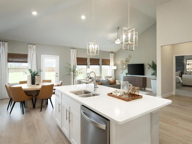 Kitchen featuring white cabinets, stainless steel dishwasher, light wood-type flooring, open floor plan, and hanging light fixtures