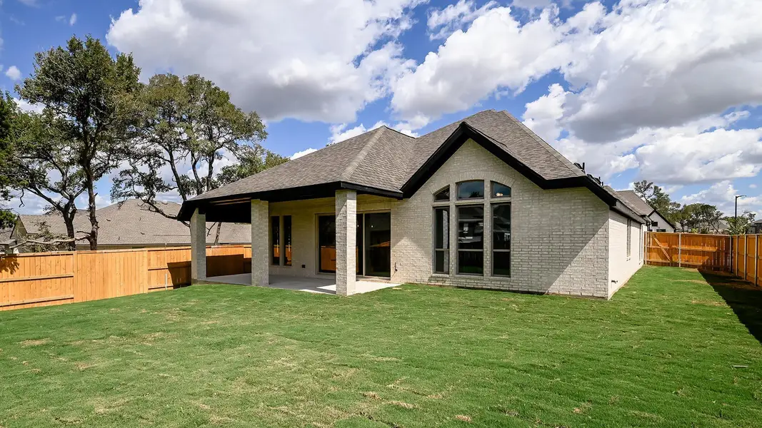 Rear view of house with a patio area, brick siding, a fenced backyard, and a shingled roof