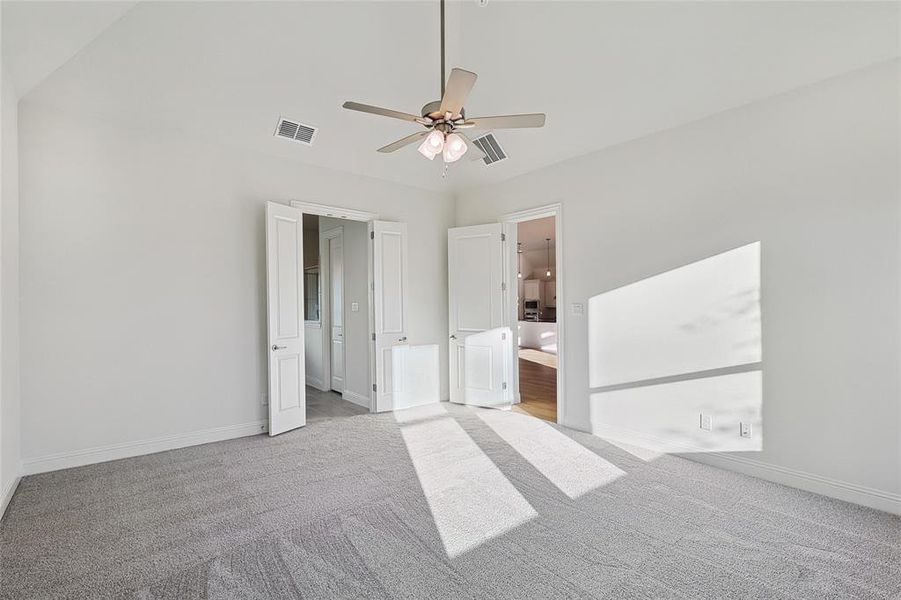 Unfurnished bedroom with light colored carpet, ensuite bathroom, and ceiling fan