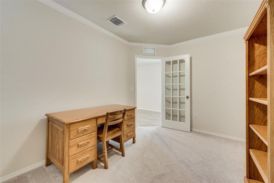 Carpeted office featuring crown molding and french door