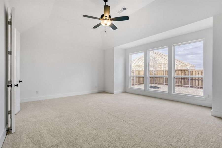 Empty room featuring light carpet, a ceiling fan, and lofted ceiling