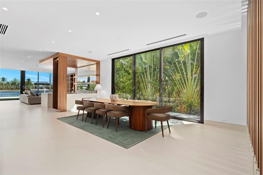 Expansive interior with light-toned flooring, full-height windows, a built-in wood-finish divider, and recessed lighting
