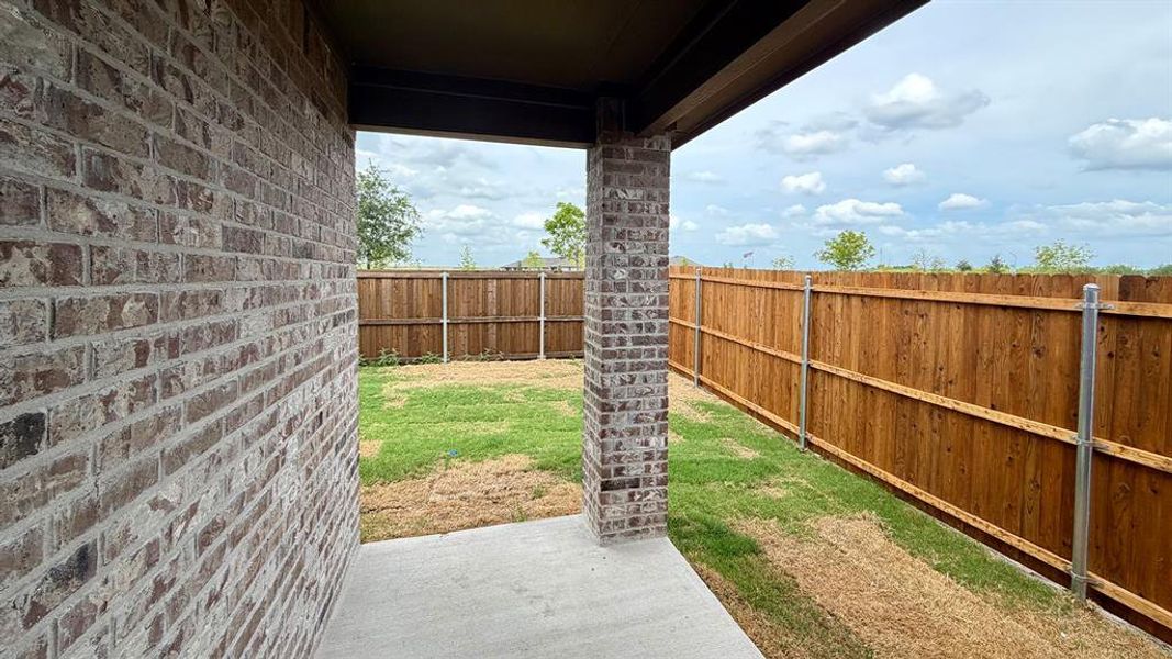 Covered patio featuring concrete flooring and a brick support pillar