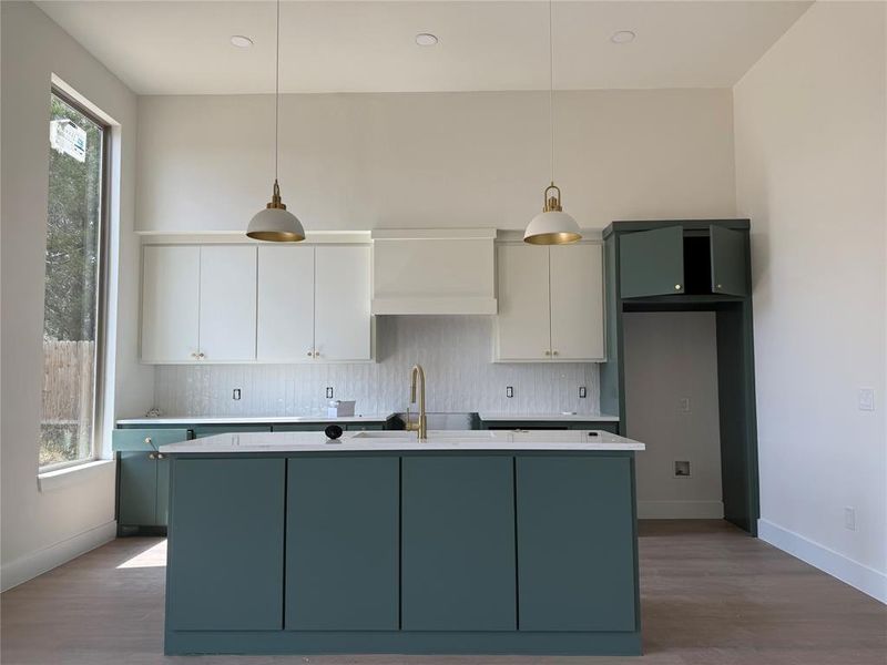 Kitchen featuring tasteful backsplash, a kitchen island with sink, white cabinetry, decorative light fixtures, and recessed lighting Kitchen featuring tasteful backsplash, a kitchen island with sink, white cabinetry, decorative light fixtures, and recessed lighting
