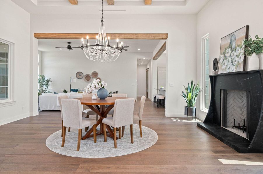 Dining room featuring a high end fireplace, wood finished floors, a chandelier, and plenty of natural light
