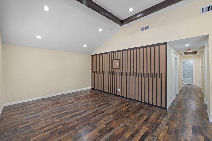 Spare room featuring high vaulted ceiling, dark hardwood / wood-style flooring, and beam ceiling