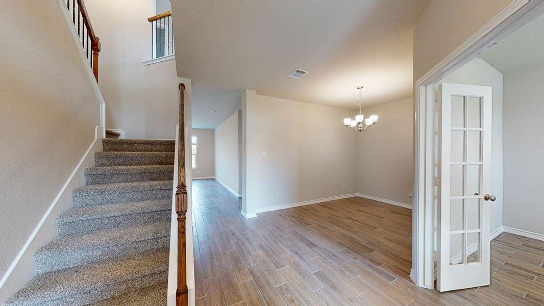 Stairs featuring a chandelier and wood finish floors Stairs featuring a chandelier and wood finish floors