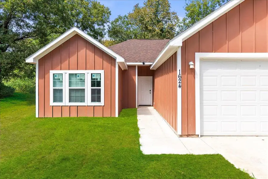 Ranch-style house featuring roof with shingles, a front yard, board and batten siding, and a garage Ranch-style house featuring roof with shingles, a front yard, board and batten siding, and a garage