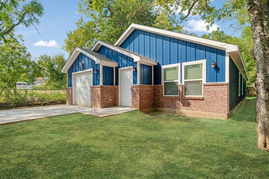 View of front of home with board and batten siding, driveway, brick siding, and a front lawn View of front of home with board and batten siding, driveway, brick siding, and a front lawn