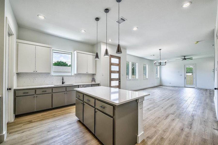 Kitchen with white cabinets, gray cabinetry, hanging light fixtures, a center island, and light hardwood / wood-style floors