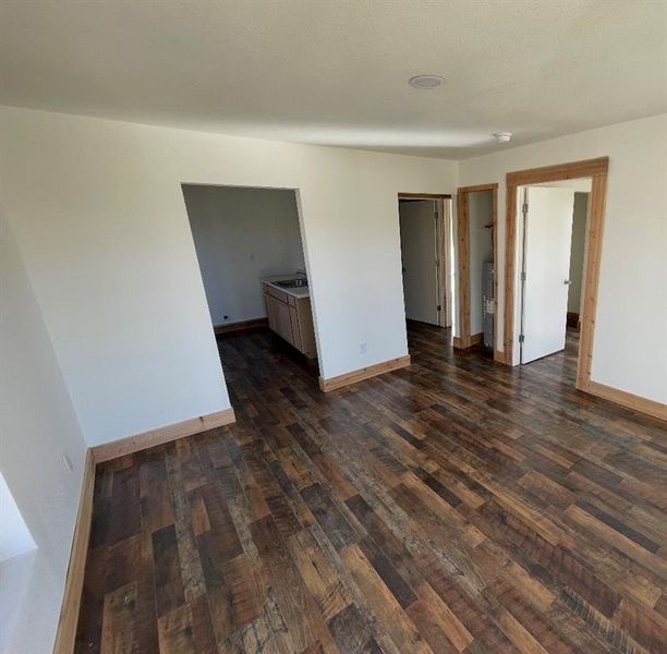 Empty room with dark wood finished floors, baseboards, and a sink
