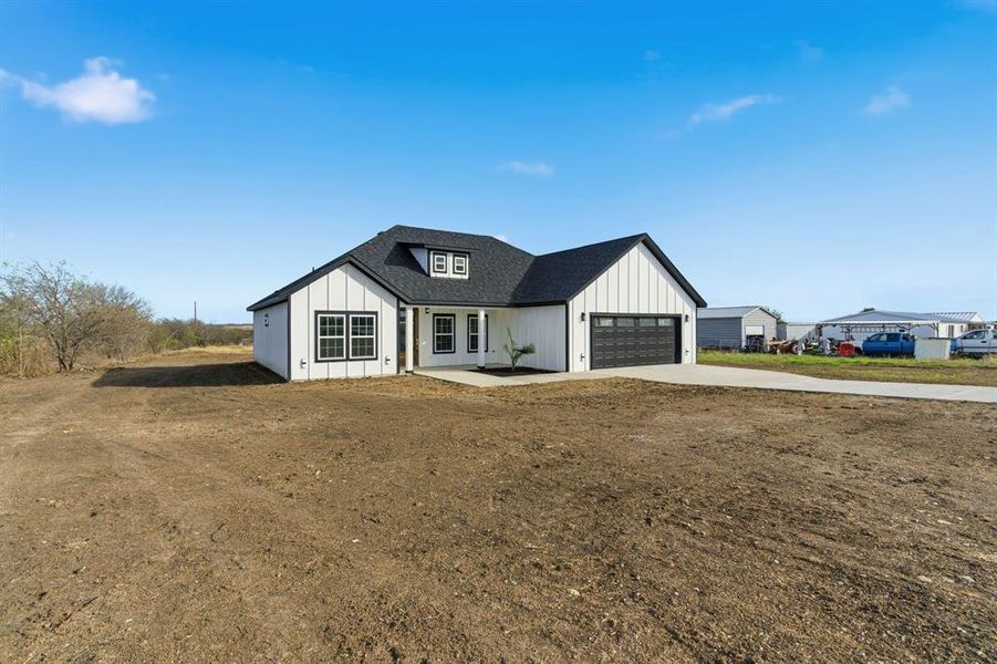 Modern inspired farmhouse featuring concrete driveway, board and batten siding, a porch, a shingled roof, and a garage