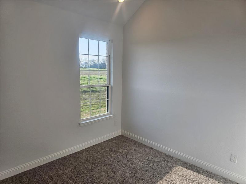 Empty room with lofted ceiling and light carpet