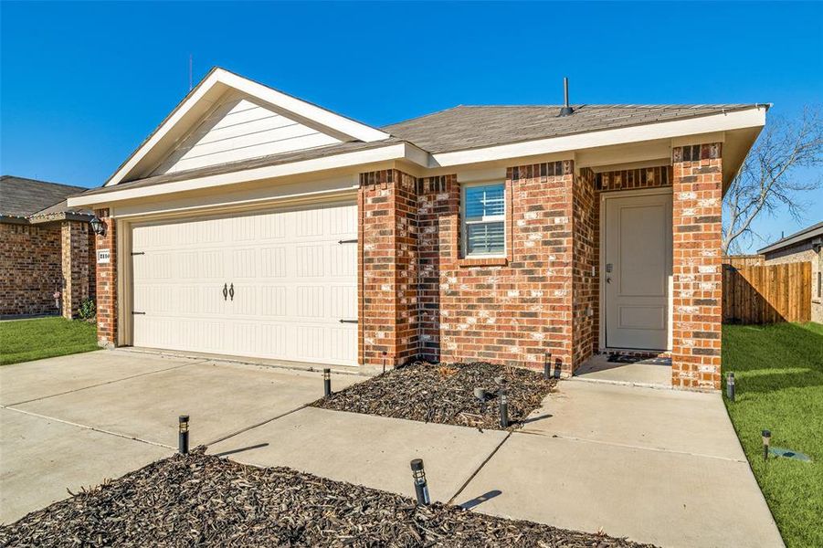 Ranch-style home with a garage, concrete driveway, brick siding, and fence