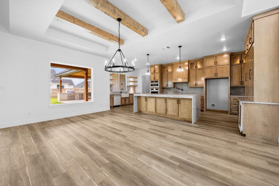 Kitchen featuring white appliances, tasteful backsplash, light wood-style flooring, beam ceiling, and brown cabinetry Kitchen featuring white appliances, tasteful backsplash, light wood-style flooring, beam ceiling, and brown cabinetry