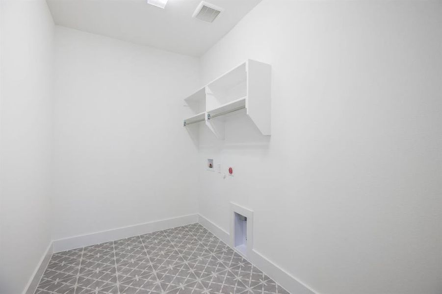 Laundry area featuring patterned floor tile, white walls, and built-in shelving with a hanging rod