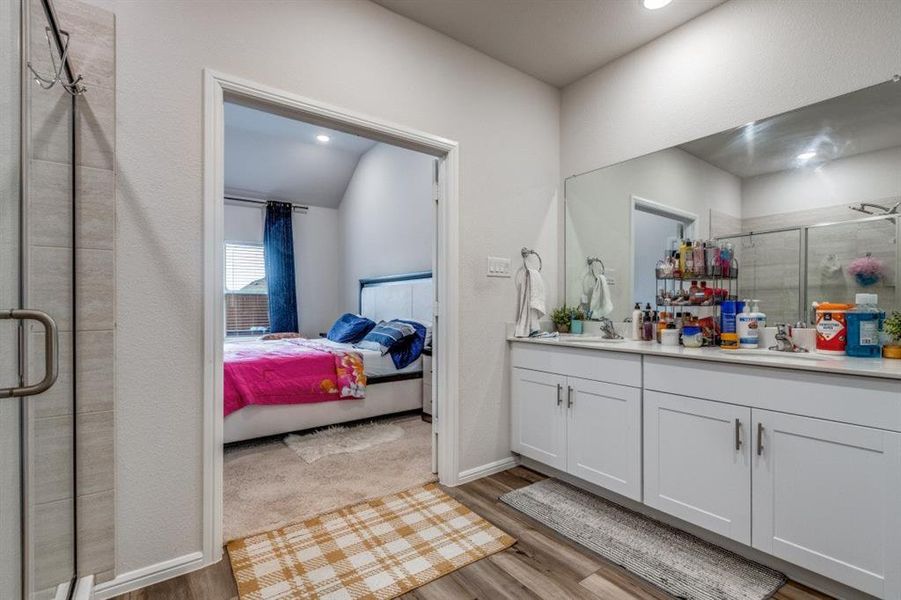 Bathroom featuring a stall shower, double vanity, light wood finished floors, and connected bathroom