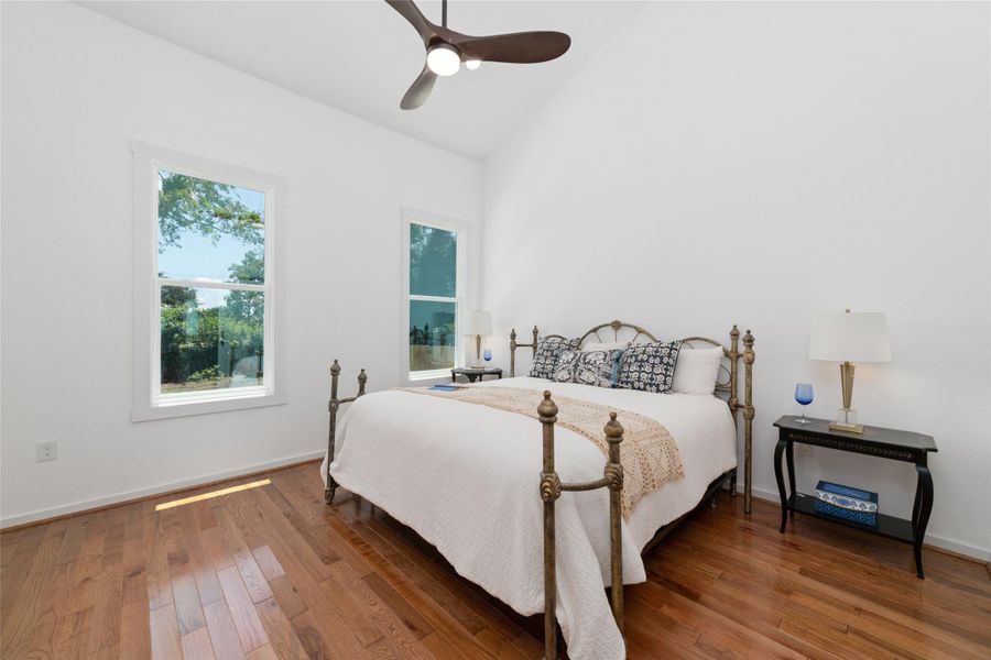 Cozy primary bedroom features hardwood floors, a ceiling fan for added comfort and ample natural light. Cozy primary bedroom features hardwood floors, a ceiling fan for added comfort and ample natural light.