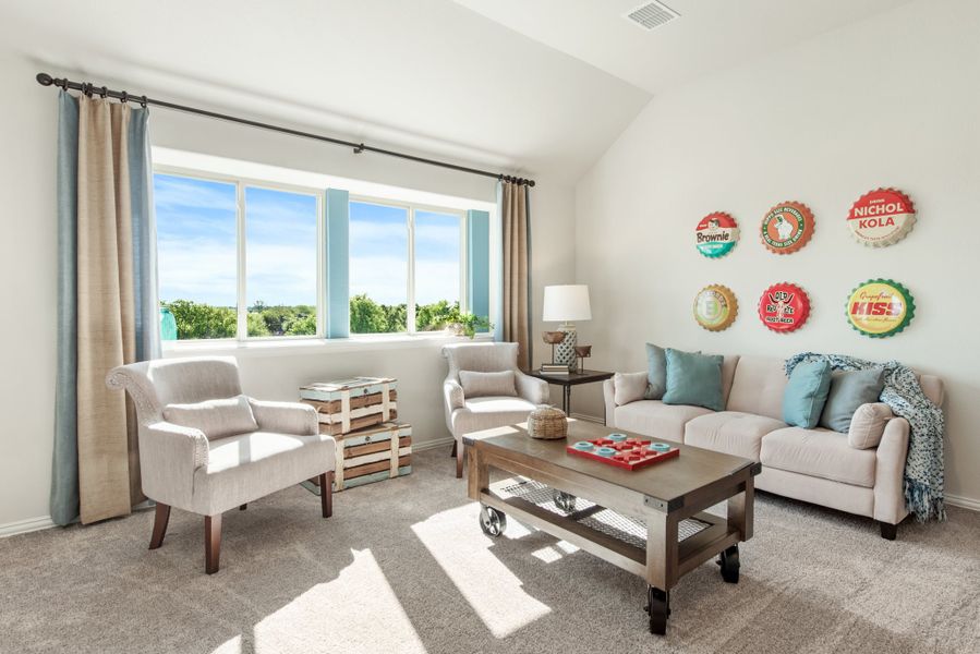 Casual living room with vaulted ceiling, neutral sofa, two armchairs, and vintage bottle cap wall decor