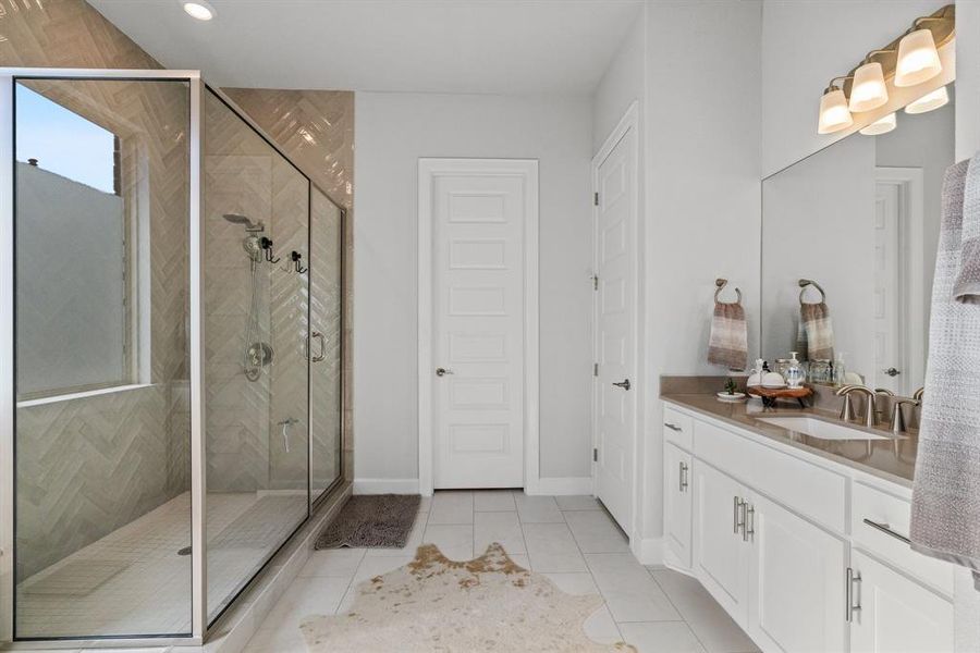 The primary bathroom has an oversized walk-in shower, separate dual vanities, and tile flooring throughout.