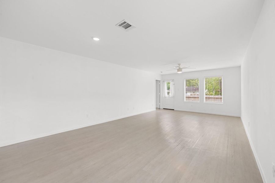 Spacious living area features light-toned flooring, neutral finishes, and a ceiling fan, with multiple windows bringing natural light into the space. Spacious living area features light-toned flooring, neutral finishes, and a ceiling fan, with multiple windows bringing natural light into the space.