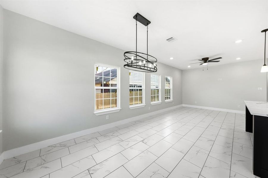 Unfurnished dining area featuring light marble finish flooring, suspended lighting, and a ceiling fan