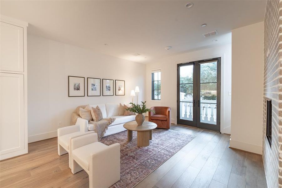 Living room with french doors, light hardwood / wood-style floors, and a brick fireplace