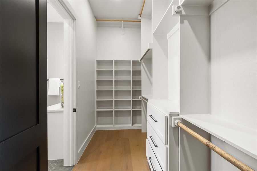 Primary walk-in closet with three levels for hanging, built-in's