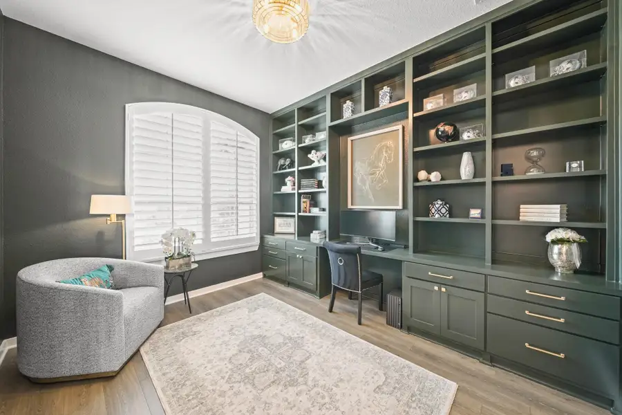 Just off the entry sits the custom built study with 8-foot French doors, a built-in desk with floor-to-ceiling bookshelves and cabinet storage, decorative chandelier with fan and custom arched plantation shutters.