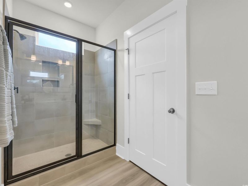 Bathroom with a stall shower, light wood-style flooring, and recessed lighting