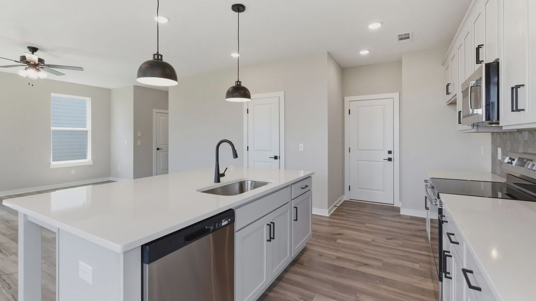 Kitchen with tile backsplash, pendant lighting, and quartz countertops