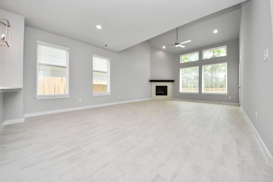 Welcome family and guests to your charming living room! With its high ceilings, recessed lighting, ceiling fan, custom paint, beautiful flooring, and large windows that let in abundant natural light, this room is perfect for gatherings.