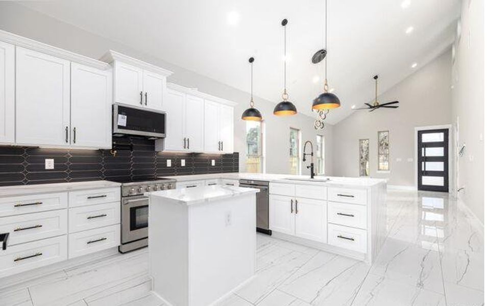 Open-concept kitchen featuring white shaker cabinetry, stainless steel appliances, a center island with a sink, black picket tile backsplash, and white marble-look flooring