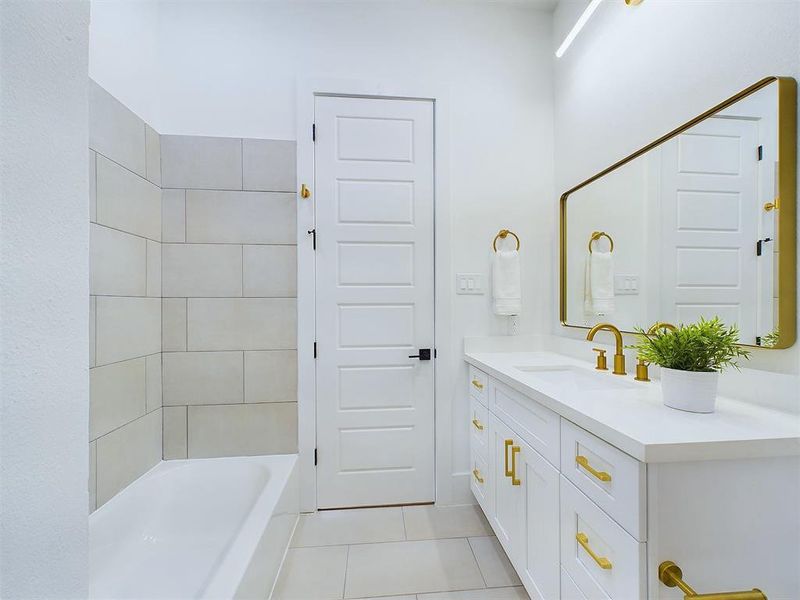 The secondary bathroom features a versatile tub and shower combination for the convenience of you and your guests. Quartz countertops exude sophistication while offering durability for everyday use. A sleek and contemporary lighting fixture brightens up the space and matches the oversized mirror seen in this photo. *All interior photos are from the model home: 9007 Orange Springs Dr.*