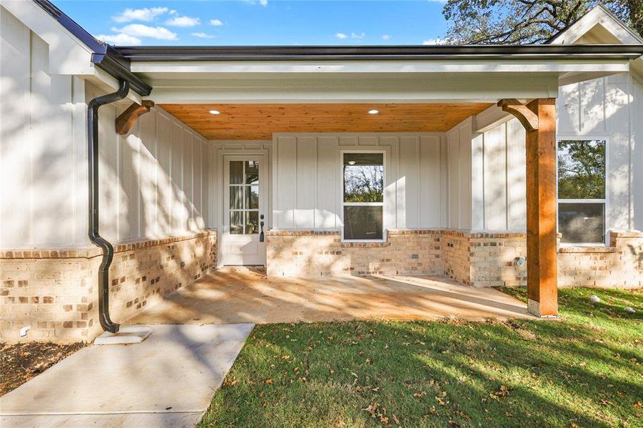 Doorway to property featuring brick siding, board and batten siding, and a yard