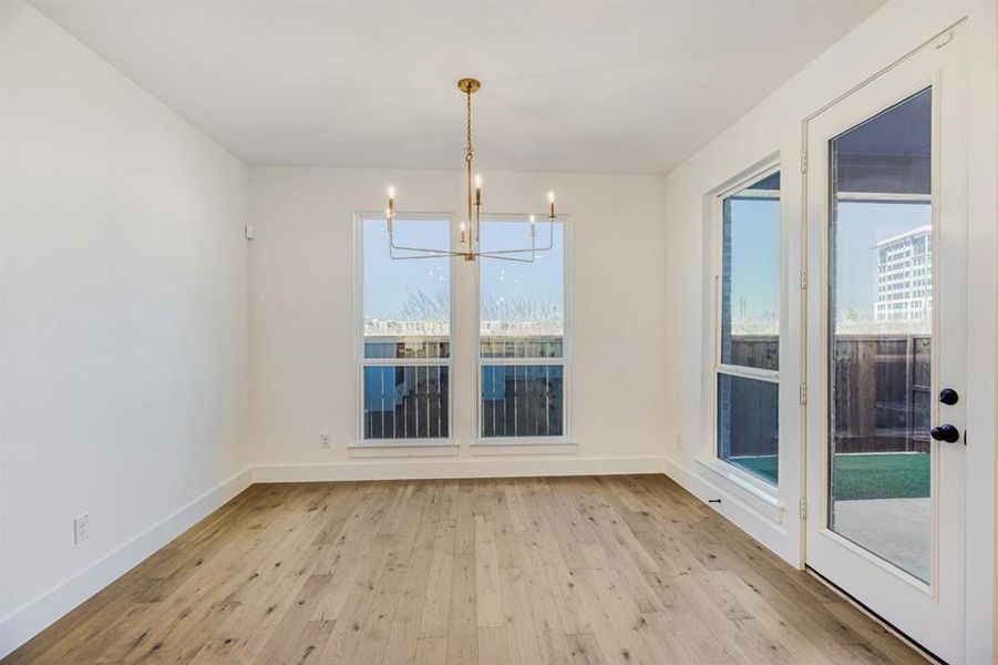 Unfurnished dining area with light wood-style flooring and suspended lighting